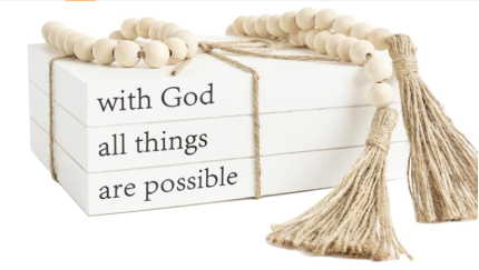 Decorative white faux books with "With God All Things Are Possible" quote, accompanied by a farmhouse bead garland with tassels.