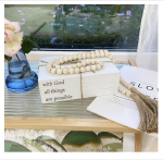 Decorative white faux books with "With God All Things Are Possible" quote, accompanied by a farmhouse bead garland with tassels.