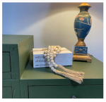 Decorative white faux books with "With God All Things Are Possible" quote, accompanied by a farmhouse bead garland with tassels.