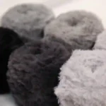 Faux fur eyelash yarn rolls in gray, ideal for knitting, crocheting, and crafting scarves and home accessories.