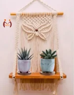 Handmade macrame wall hanging shelf with natural wood and white twiner for home decoration.